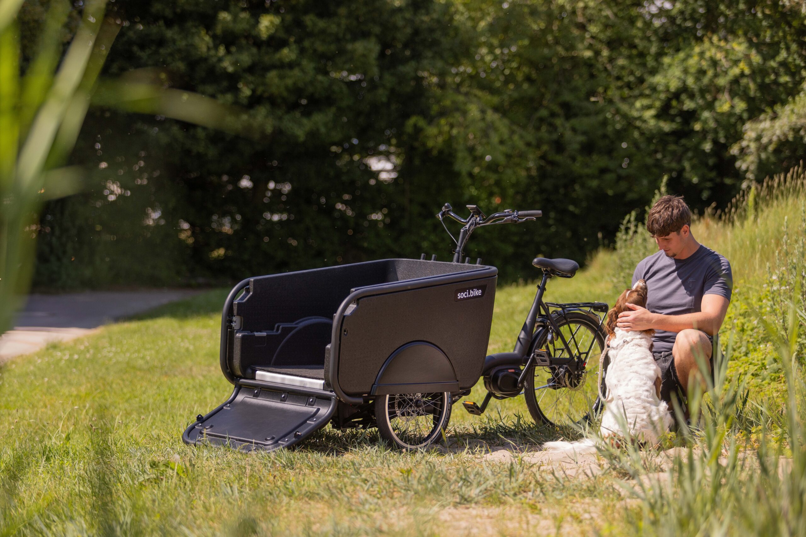 Een SociBike Family met naast de fiets een baasje met een hond.